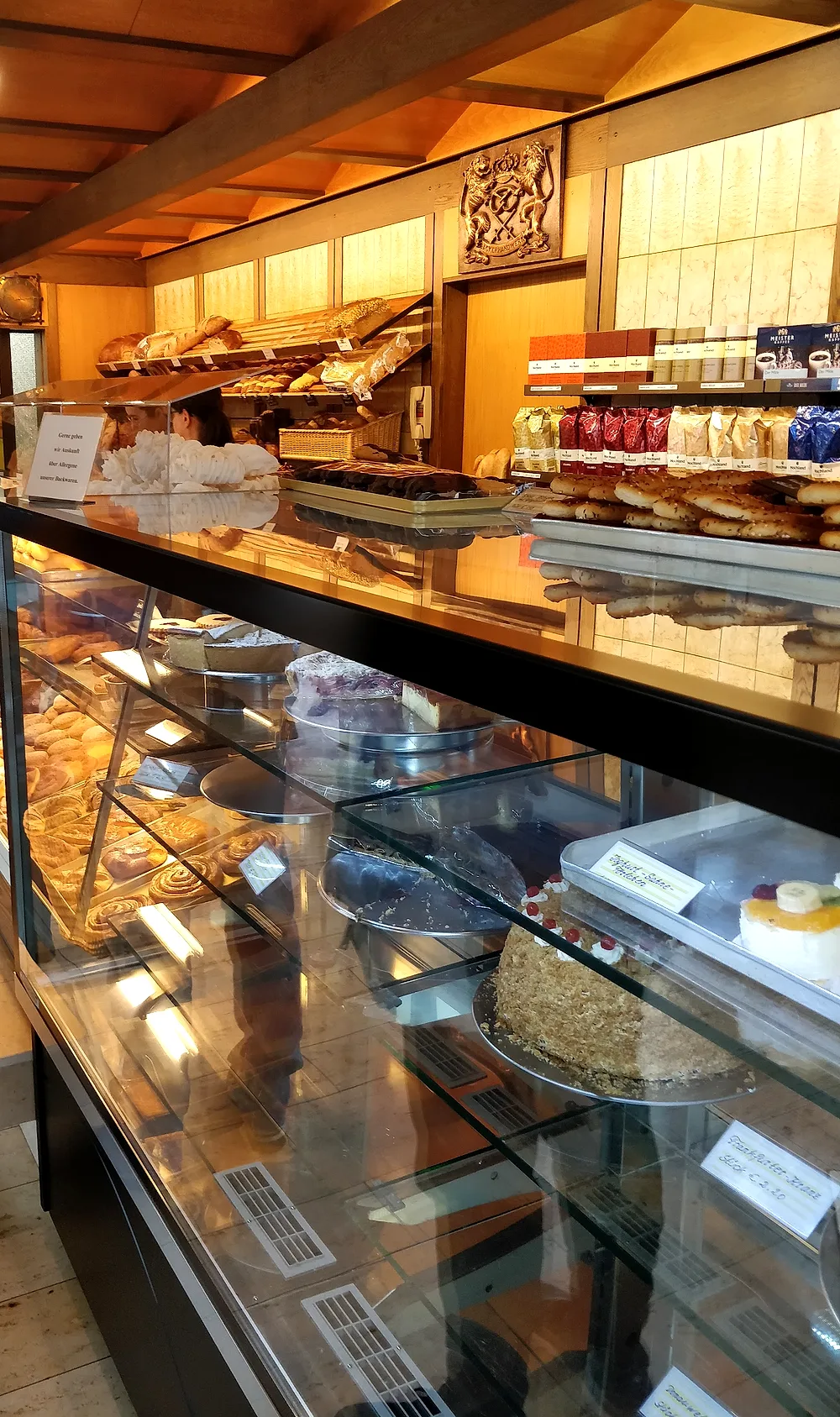 Blick in die Bäckerei Schütz: warme Holztheke mit Broten, Kuchen und Torten in der Glasvitrine